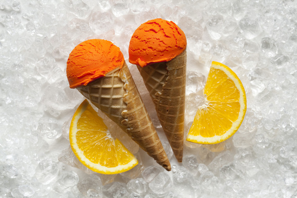 Ice cream, cone and orange slices on ice cubes - Foto, imagen