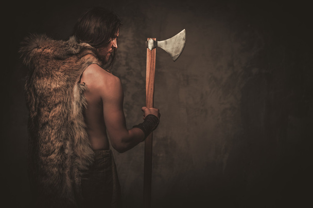 Angry viking with ax in a traditional warrior clothes - Fotoğraf, Görsel