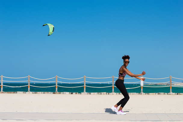 One african female jogging at the Dubai beach in UAE. Young african woman having fun at the seaside - Photo, Image