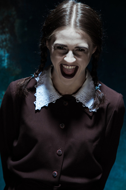 Portrait of a young smiling girl in school uniform as killer woman - Zdjęcie, obraz