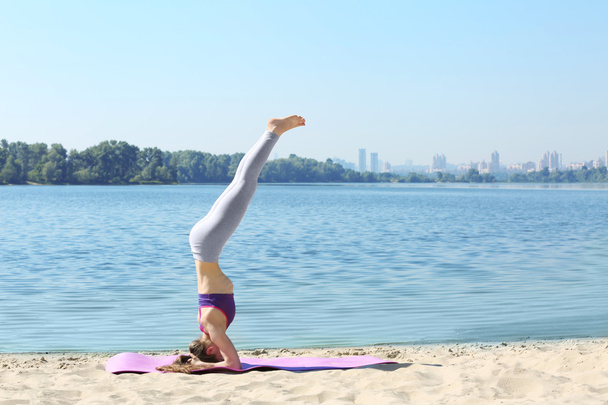 young woman doing yoga by the river - Foto, Imagen