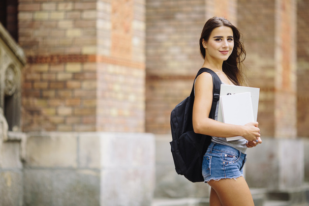 sonriente chica universitaria está sosteniendo libro
 - Foto, Imagen