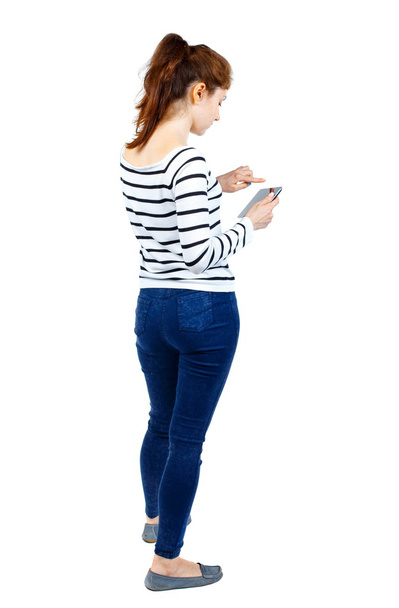 back view of standing young beautiful  woman using a mobile phon - 写真・画像