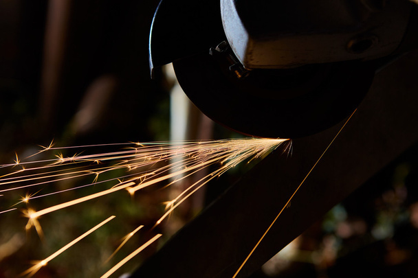 Worker cutting metal with grinder. Sparks while grinding iron - Photo, Image