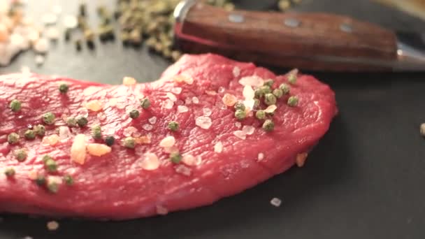 raw beef meat fillet with peppercorn and thyme and differnt spices in glass bottles ready to grill on wood figured aged board over table 1920x1080 intro motion slow hidef hd - Záběry, video