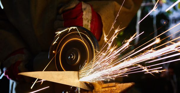 Worker cutting metal with grinder. Sparks while grinding iron - Photo, Image