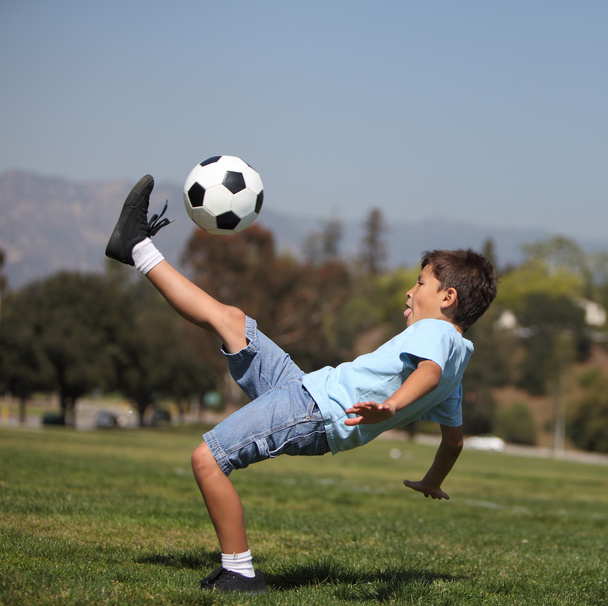 хлопчик штовхає футбольний м'яч
 - Фото, зображення