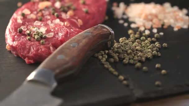 raw beef meat fillet with peppercorn and thyme and differnt spices in glass bottles ready to grill on wood figured aged board over table 1920x1080 intro motion slow hidef hd - Filmati, video
