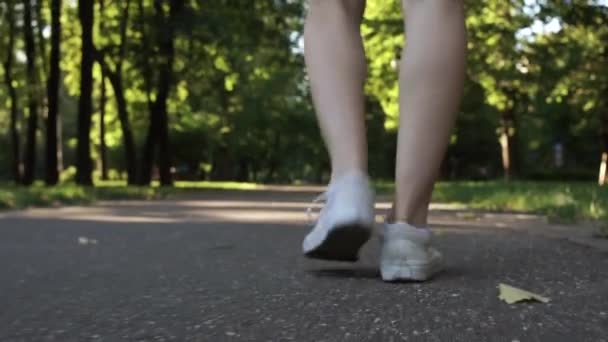 Młoda kobieta nogi spaceru w parku - Materiał filmowy, wideo