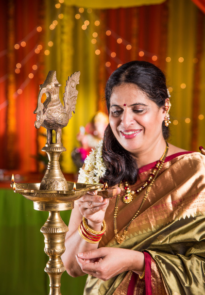 Indická žena v tradiční Saree Lighting olejová lampa nebo samai s Díja a oslavující slavnost ganeš nebo Diwali nebo Deepavali. Indická dáma držící olejovou svítilnu uvnitř. - Fotografie, Obrázek