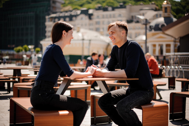 Young, happy couple smiling and holding hands across the table at a restaurant. - Fotografie, Obrázek