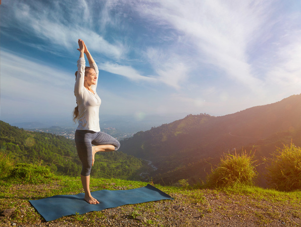 Mujer en yoga asana Vrikshasana pose árbol en las montañas al aire libre - Foto, Imagen