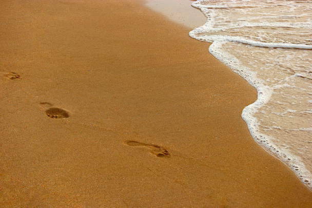 Playa de arena, olas y pasos retroiluminados al atardecer
 - Foto, imagen