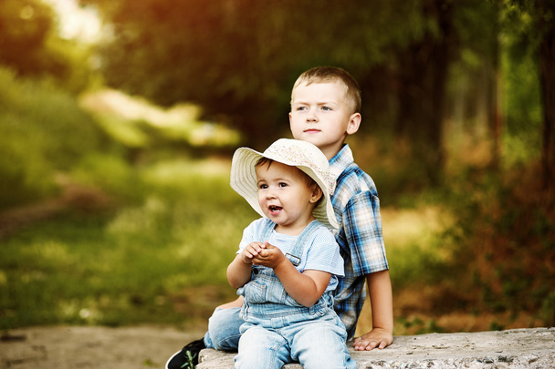 Zabawny dziewczynka siedzi ze swoim bratem w parku - Zdjęcie, obraz
