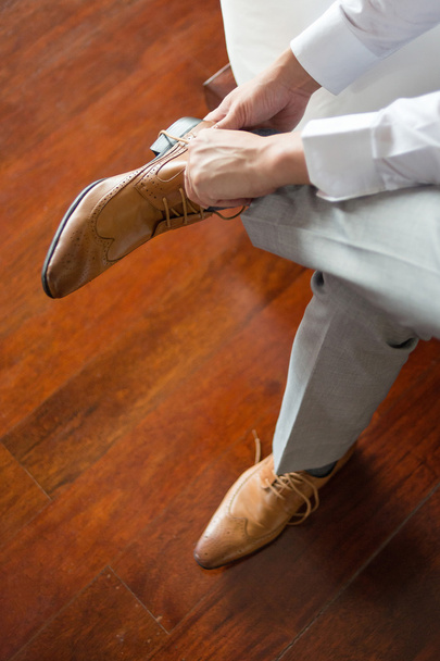 Businessman or groom wearing his brown shoes - Fotoğraf, Görsel