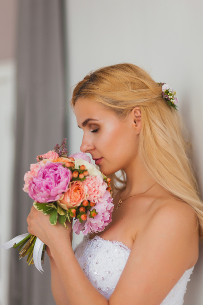 Portrait of a beautiful blonde bride with bouquet in an interior light, wedding concept - Fotografie, Obrázek