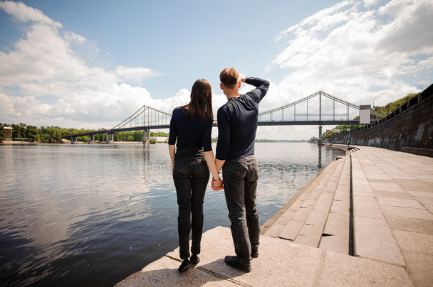 Молодая пара мужчина и женщина стоят на берегу реки
 - Фото, изображение