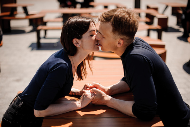 young and attractive couple holding hands  about to kiss over table in restaurant - Фото, изображение