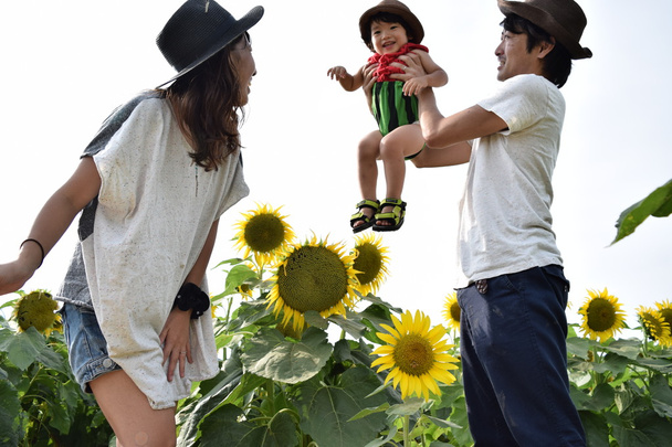 young family is smiling with sunflower field - Photo, Image