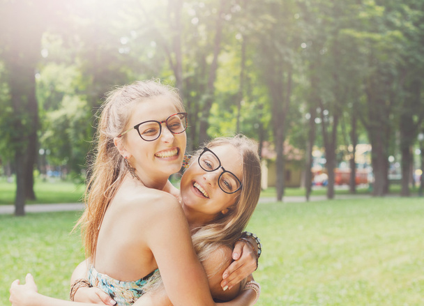 Two happy young girls hug each other in summer park - Foto, Imagem