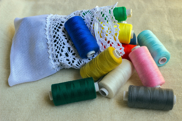 Accesorios de costura. Bobinas hilos de diferentes colores y bolsa blanca para almacenamiento
  - Foto, Imagen