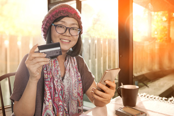 Счастье эмоции азиатской женщины с кредитной картой в руке использования FO
 - Фото, изображение