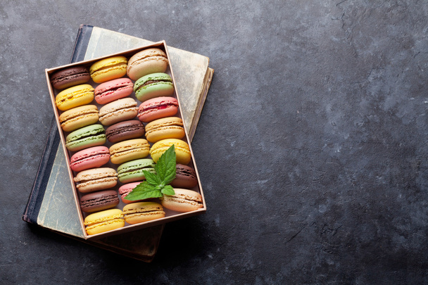 Colorful macaroons in box over book - Photo, Image