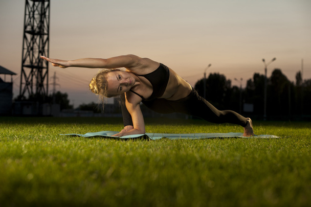 Mujer rubia ejercitando yoga sobre hierba verde al aire libre
 - Foto, imagen