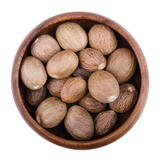 Nutmegs in a bowl over white - Photo, Image