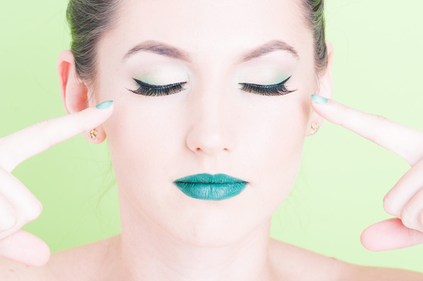 Woman wijzend op haar ogen professionele glamoureuze make-up dragen - Foto, afbeelding