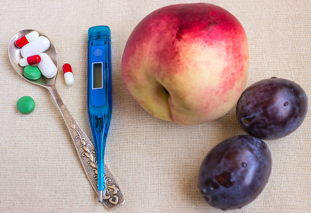 Various pills, spoon and thermometer. Fruits contain a lot of vitamins. - Photo, Image