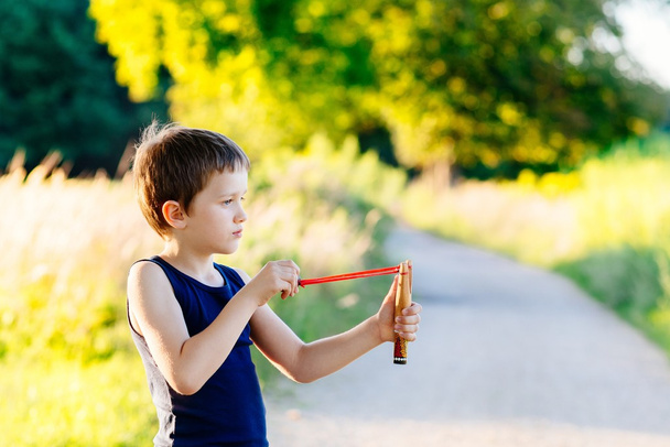 Little boy playing with slingshot - Photo, Image