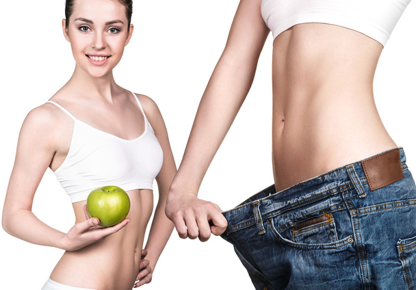 Menina segurando uma maçã e vestindo jeans grandes
 - Foto, Imagem