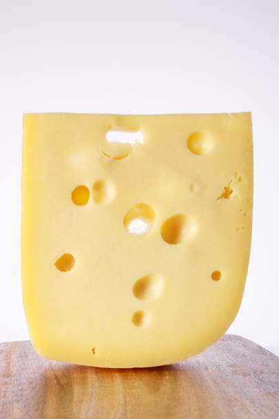 milk product. piece  cheese with big holes.a piece of cheese with the large holes on a light background with a gradient. alpinland. - Foto, imagen