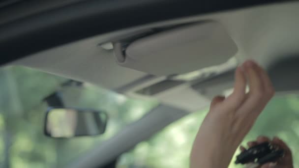 Mujer ocultando la llave de encendido en el visor de sol del coche
 - Metraje, vídeo