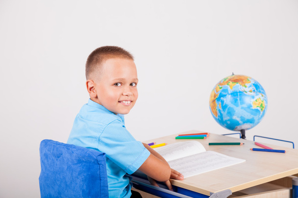 хлопчик сидить за своїм столом і робить домашнє завдання
 - Фото, зображення