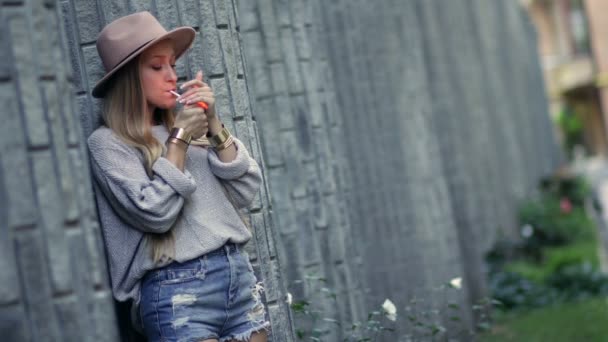 Γυναίκα που καπνίζει και ακουμπά στον τοίχο τούβλου loft - Πλάνα, βίντεο
