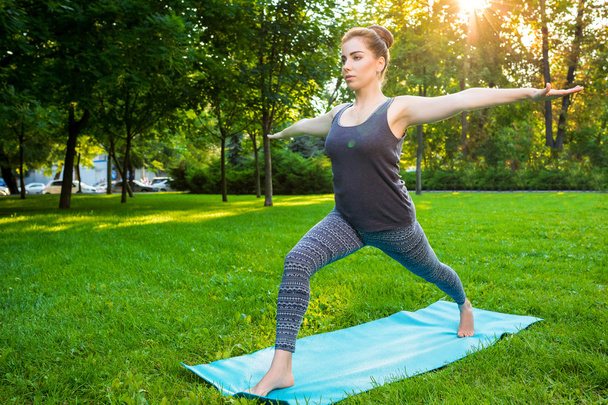 Młoda kobieta robi ćwiczenia jogi w parku miejskim lato. - Zdjęcie, obraz