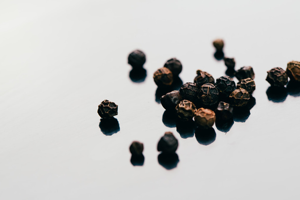 black peppercorns on a dark mirror background close-up - Фото, изображение