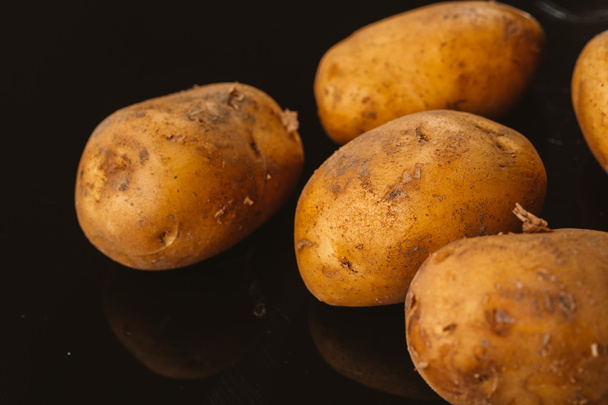 Fresh raw potatoes on a black background - Photo, Image