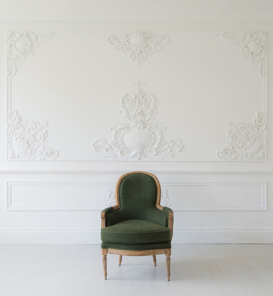Sala de estar com antigo elegante poltrona verde na parede branca de luxo design baixo relevo estuque molduras elementos rococó
 - Foto, Imagem