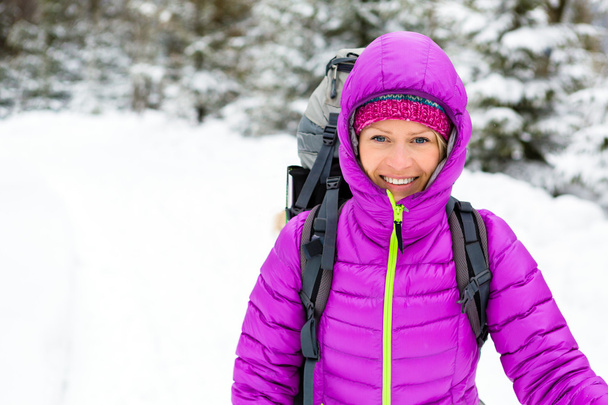Happy woman walking in winter forest with backpack - Photo, Image