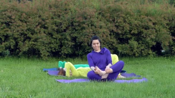Yoga in the Park. Two Girls Doing the Bridge Pose and One Lotos Pose. - Footage, Video