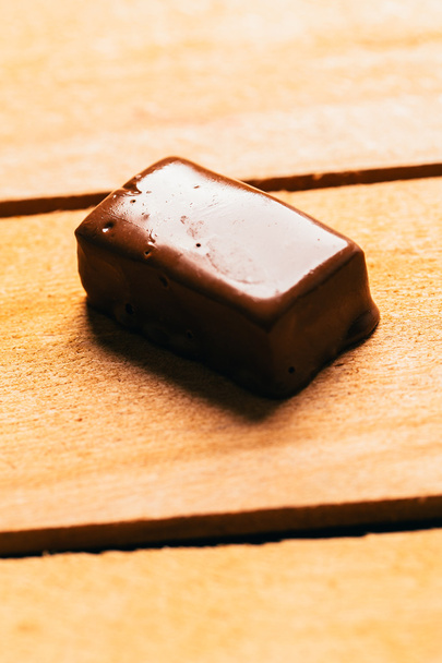 Одна шоколадна цукерка на дерев'яному фоні
 - Фото, зображення