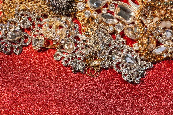 Golden and silver jewelry on red shiny glitter background - Foto, imagen