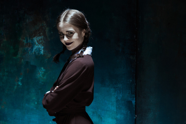 Portrait of a young smiling girl in school uniform as killer woman - 写真・画像