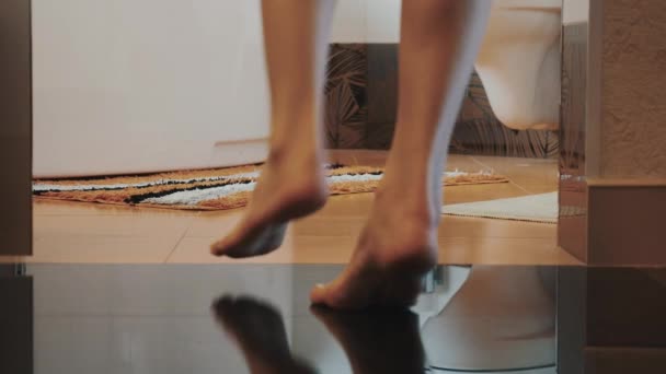 Женщина с голыми ногами ходит в ванную и садится на унитаз. Сними нижнее белье.
 - Кадры, видео