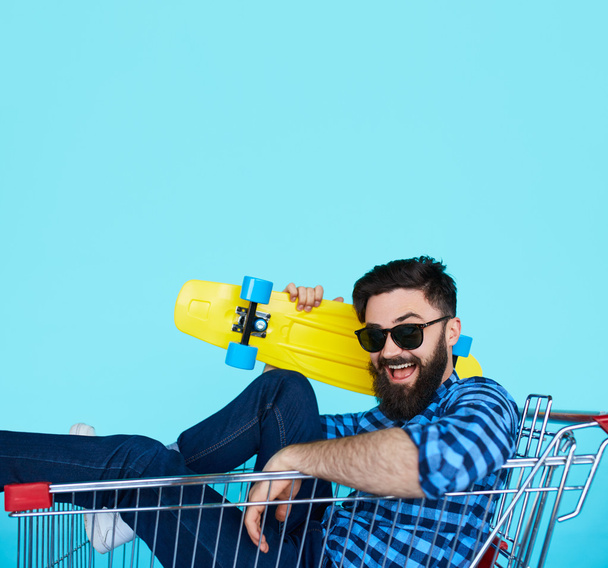 Young man sitting in shopping cart - 写真・画像