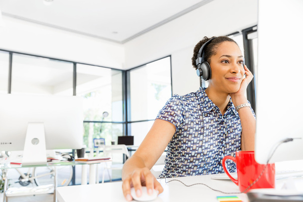 Portrait of smiling afro-american office worker sitting in offfice with headphones - Foto, Bild