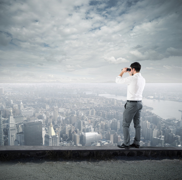 Бизнесмен смотрит на город с биноклем
 - Фото, изображение